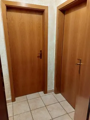 a hallway with two wooden doors and a tile floor at Carezza Lake Apartment in Carezza al Lago