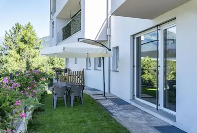 a patio with a table and chairs and a umbrella at Agritur Gioia in Sanzeno