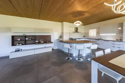 a kitchen with white cabinets and a wooden ceiling at Agritur Gioia in Sanzeno