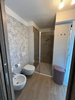 a bathroom with a shower and a toilet and a sink at Residenza Erica in Moena