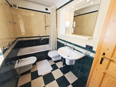 a bathroom with two toilets and a sink and a tub at La Fata di Moena - Alpine Stay Apartments in Moena