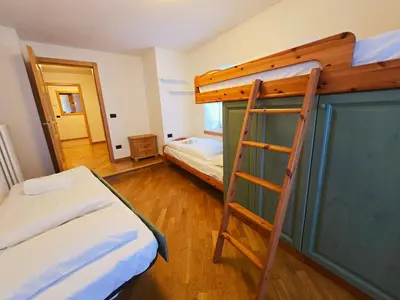 a bedroom with two bunk beds and a ladder at La Fata di Moena - Alpine Stay Apartments in Moena