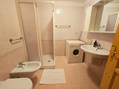 a bathroom with a toilet sink and a washing machine at La Fata di Moena - Alpine Stay Apartments in Moena