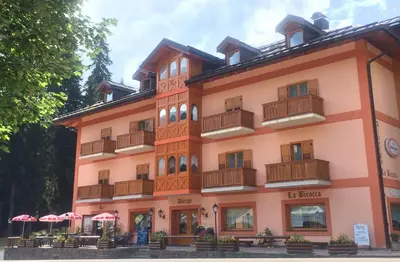 a large building with tables and umbrellas in front of it at Albergo La Bicocca in Paneveggio