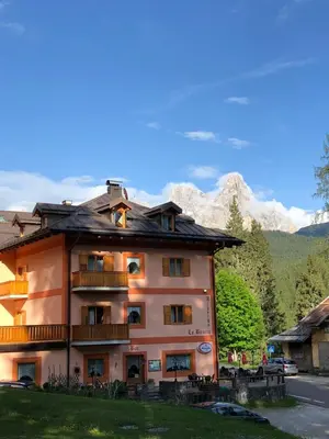 a building with a balcony and mountains in the background at Albergo La Bicocca in Paneveggio