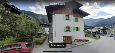 a small house with a red car parked in front of it at Appartamento Alba sulle Dolomiti in Falcade