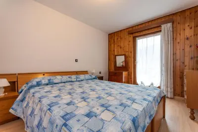 a bedroom with a large bed and a window at Appartamento Alba sulle Dolomiti in Falcade