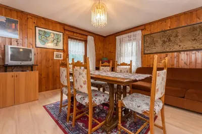 a dining room with a table and chairs and a television at Appartamento Alba sulle Dolomiti in Falcade