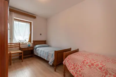 a bedroom with two beds and a desk and a window at Appartamento Alba sulle Dolomiti in Falcade