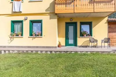 a house with two chairs and two windows with flowers at Casa Serena in Dolomiti Agordine in Taibon