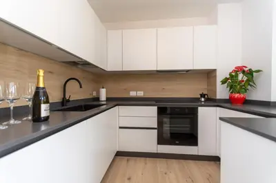 a kitchen with white cabinets and a bottle of wine at Casa Serena in Dolomiti Agordine in Taibon