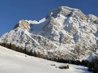 a snow covered mountain with a house in front of it at Wirthof in La Valle