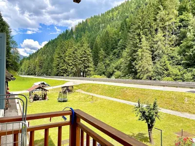 a balcony with a view of a field with trees at Appartamento vicino agli impianti Predazzo in Predazzo