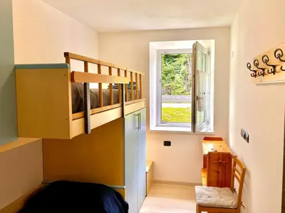 a small room with a bunk bed and a window at Appartamento vicino agli impianti Predazzo in Predazzo