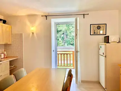 a kitchen with a table and a refrigerator and a window at Appartamento vicino agli impianti Predazzo in Predazzo