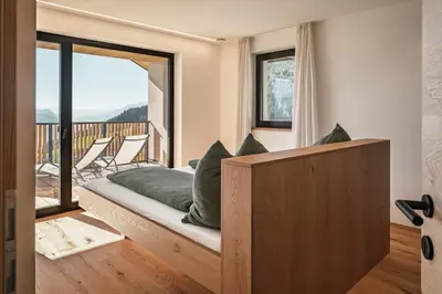 a room with a bed and a balcony with chairs at Oachner Living in Feldthurns