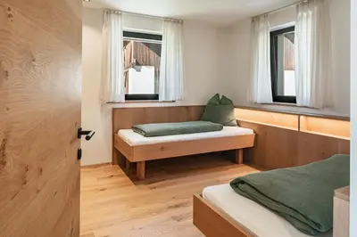 a bedroom with two beds and two windows at Oachner Living in Feldthurns