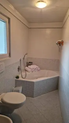 a bathroom with a bath tub and a toilet at Ciasa Rungger in San Martino in Badia