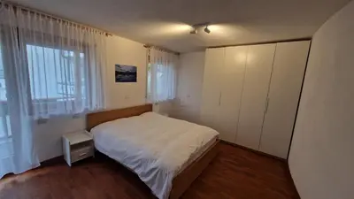 a bedroom with a white bed and a large window at Ciasa Rungger in San Martino in Badia