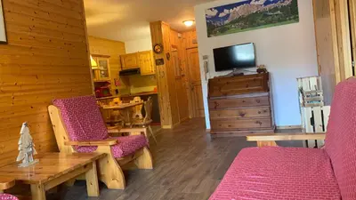 a living room with two chairs and a table and a tv at Appartamento Stella Alpina con sauna piscina palestra e posto auto in Cavalese