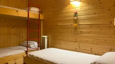 a bedroom with two bunk beds and a wooden wall at Appartamento Stella Alpina con sauna piscina palestra e posto auto in Cavalese