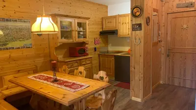 a kitchen with a wooden table in a room at Appartamento Stella Alpina con sauna piscina palestra e posto auto in Cavalese