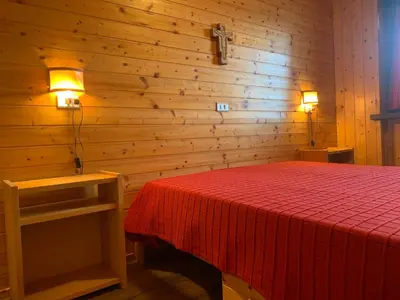 a bedroom with a red bed with two lights on it at Appartamento Stella Alpina con sauna piscina palestra e posto auto in Cavalese