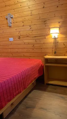 a bedroom with a bed and a cross on the wall at Appartamento Stella Alpina con sauna piscina palestra e posto auto in Cavalese