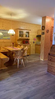 a kitchen with a table and chairs in a room at Appartamento Stella Alpina con sauna piscina palestra e posto auto in Cavalese