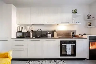 a kitchen with white cabinets and a stove top oven at Appartamento Pineta casa vacanze Sci & Natura in Varena