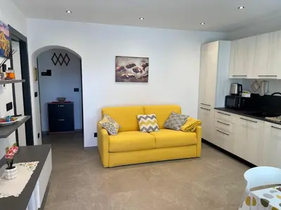 a living room with a yellow couch in a kitchen at Appartamento Pineta casa vacanze Sci & Natura in Varena