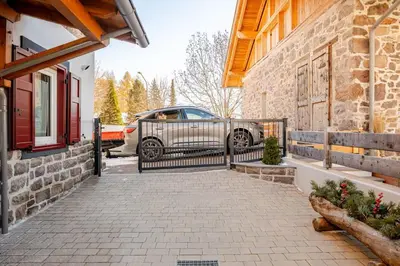a car parked next to a house with a fence at Appartamento Pineta casa vacanze Sci & Natura in Varena