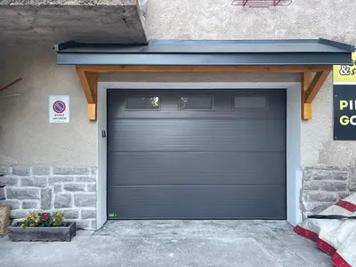 a garage with a blue garage door on the side of a building at Appartamento Pineta casa vacanze Sci & Natura in Varena