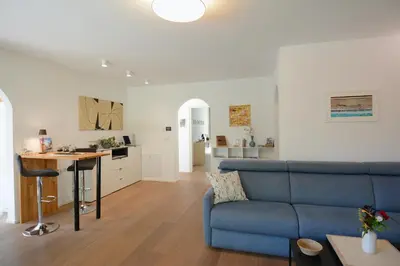 a living room with a blue couch and a kitchen at maia garden - apartment & private garden in Merano