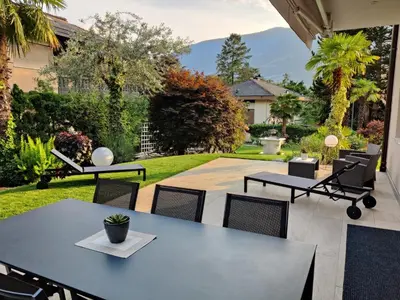 a patio with tables and chairs and a yard at maia garden - apartment & private garden in Merano