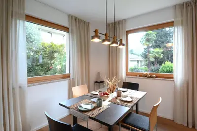 a dining room with a table and two windows at maia garden - apartment & private garden in Merano