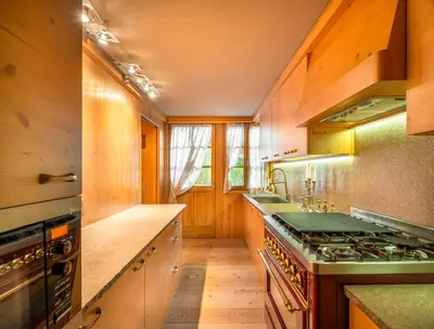 a kitchen with wooden cabinets and a stove top oven at Elegant Tablà with Garden R&R in Cortina dʼAmpezzo