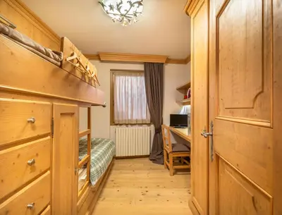 a bedroom with a bed and a desk in a room at Elegant Tablà with Garden R&R in Cortina dʼAmpezzo