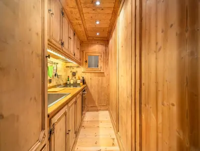 a kitchen with wooden walls and a wooden floor at Elegant Tablà with Garden R&R in Cortina dʼAmpezzo