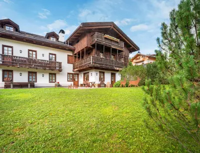 a large house with a green lawn in front of it at Elegant Tablà with Garden R&R in Cortina dʼAmpezzo