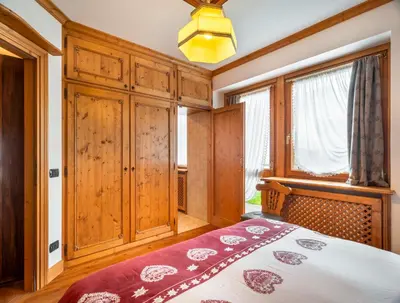 a bedroom with a bed and a chandelier at Verocai Charming Chalet R&R in Cortina dʼAmpezzo