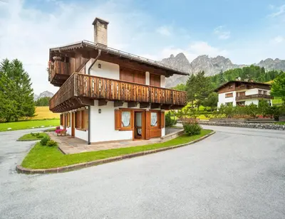 a house with a balcony on the side of a road at Verocai Charming Chalet R&R in Cortina dʼAmpezzo