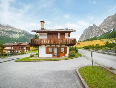 a house in the middle of a road with mountains at Verocai Charming Chalet R&R in Cortina dʼAmpezzo