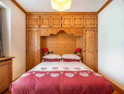 a bedroom with a bed with a wooden headboard at Verocai Charming Chalet R&R in Cortina dʼAmpezzo