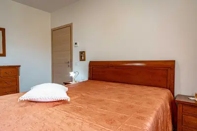 a bedroom with a large bed with a wooden headboard at Dimora Kino, Taio Ospitar in Taio