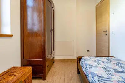 a bedroom with a bed and a wooden cabinet at Dimora Kino, Taio Ospitar in Taio