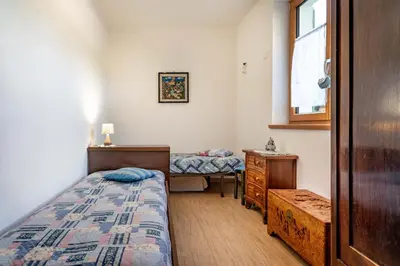 a bedroom with two beds and a dresser and a window at Dimora Kino, Taio Ospitar in Taio