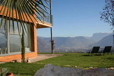 a house with chairs sitting on a lawn with mountains in the background at Kreuzsteinhof in San Paolo