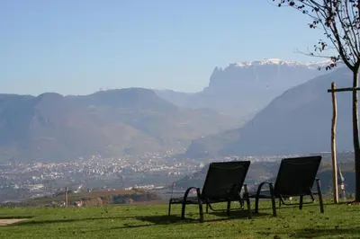 two chairs sitting on top of a field with a mountain at Kreuzsteinhof in San Paolo