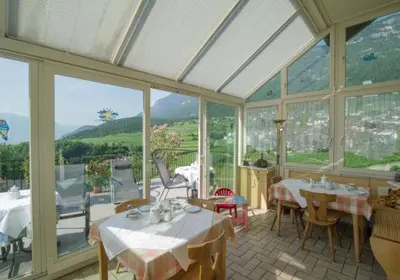 a dining room with tables and chairs and windows at Gästehaus Zugal in Caldaro
